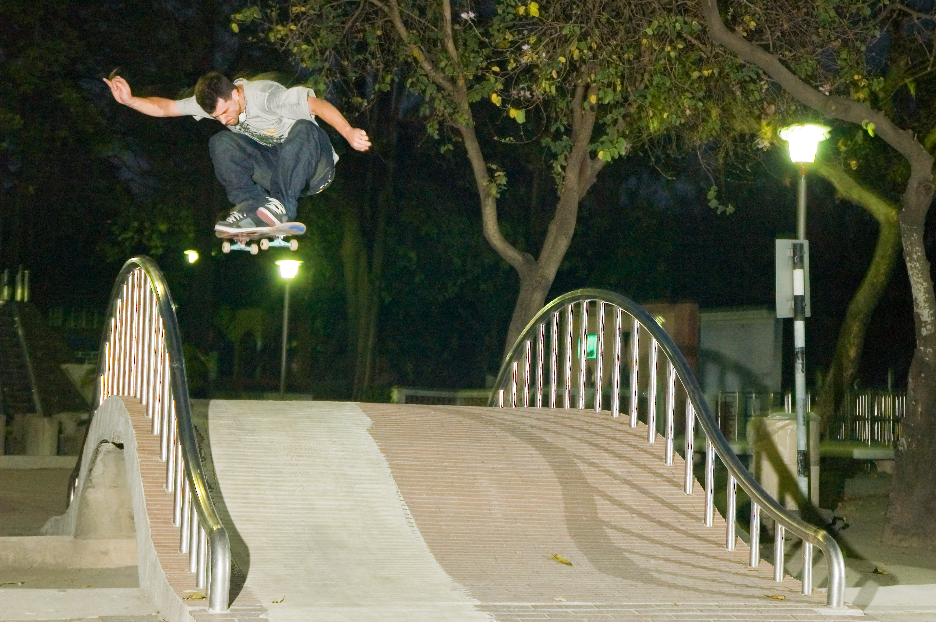 Vaughan skating over the crest of a pedestrian bridge at night