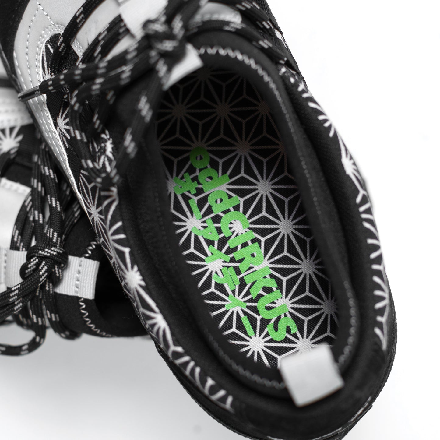 Close-up of a sneaker with a geometric pattern and green branding on a white background